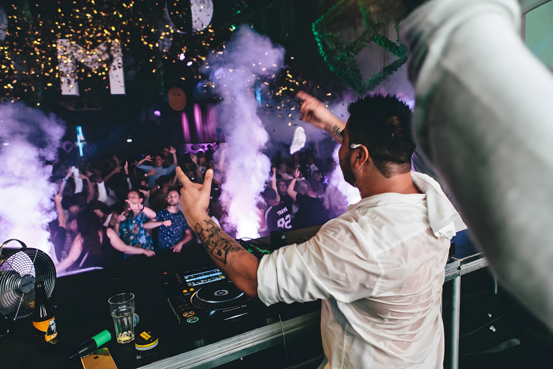 Behind the booth over a purple-lit dancefloor